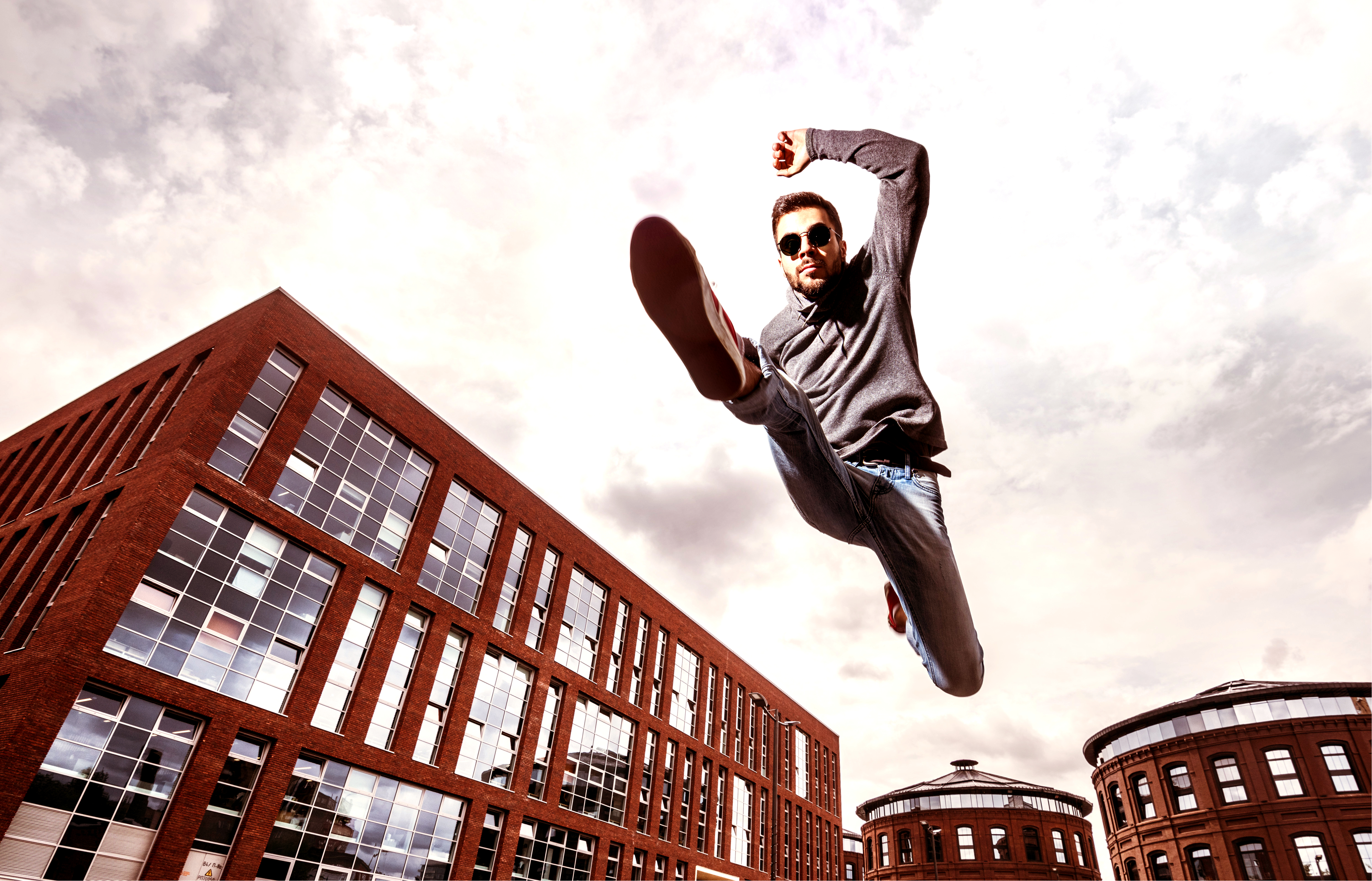 Man Jumping Down the Street in front of red building