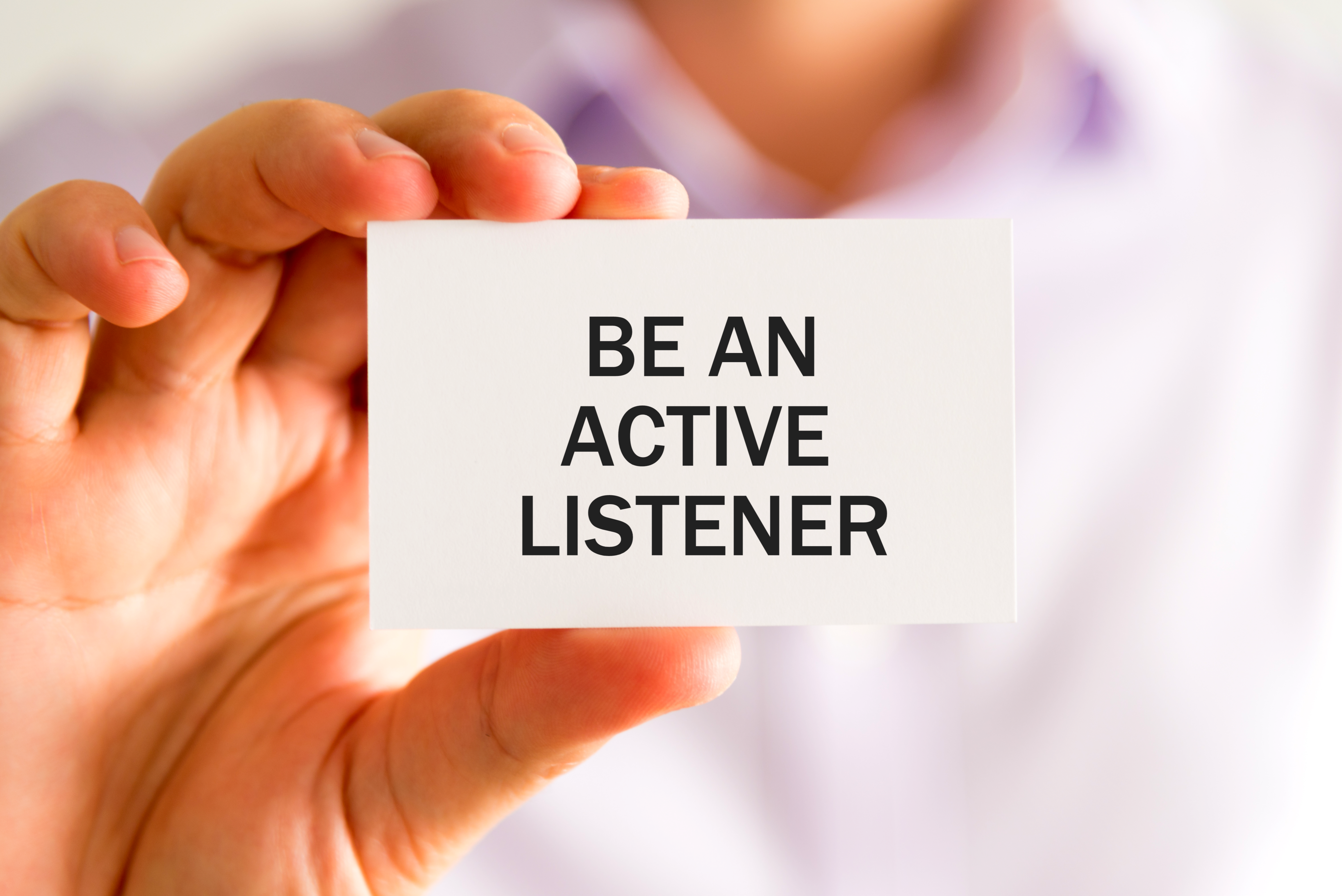 Businessman holding a card saying Active Listener as a key to not failing in Sales 